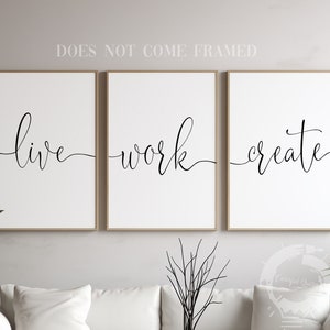 May include: Three black and white prints with the words "live", "work", and "create" in a cursive font. The prints are framed in a light wood frame and are hanging on a white wall.