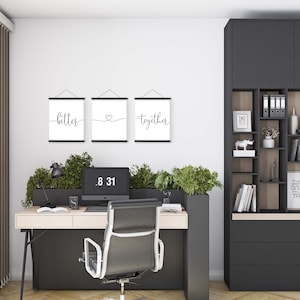 K&ouml;nnte beinhalten: Drei schwarze gerahmte Drucke mit wei&szlig;en Hintergr&uuml;nden, die an einer wei&szlig;en Wand h&auml;ngen. Die Drucke zeigen die W&ouml;rter "better", ein Herz und "together" in schwarzer Kursivschrift.