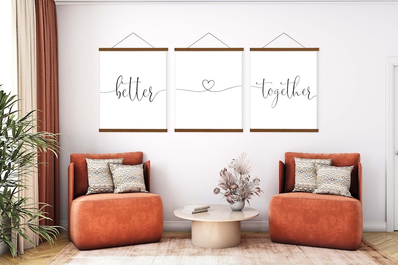 K&ouml;nnte beinhalten: Drei gerahmte Drucke mit den Worten "better", einem Herzsymbol und "together" in schwarzer Kalligraphie auf wei&szlig;em Hintergrund. Die Drucke h&auml;ngen an einer wei&szlig;en Wand &uuml;ber zwei orangen Sesseln mit gemusterten Kissen.