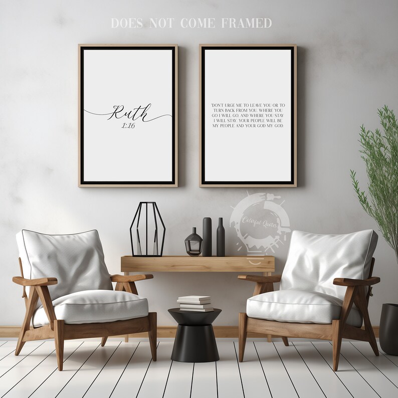 May include: Two black framed prints with white backgrounds and black text. The left print has the word "Ruth" in cursive script and the text "1:16". The right print has a bible verse from Ruth 1:16. The prints are displayed on a white wall above a wooden console table with two white armchairs.