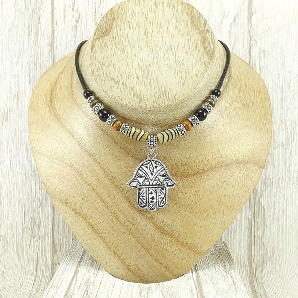 Collier ras du cou ethnique tribal de style boho avec main de Fatma montée en pendentif. Cordon cuir, métal argenté, inox, verre, bois, os.