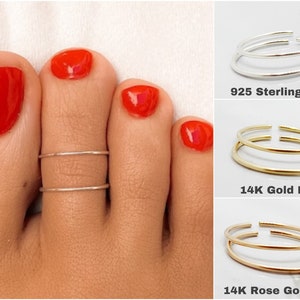 Peut inclure: Gros plan d'un pied portant une bague d'orteil à double bande. La bague est disponible en trois finitions : argent sterling 925, plaqué or 14 K et plaqué or rose 14 K.