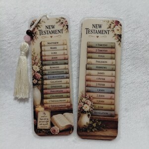 Könnte beinhalten: Zwei rechteckige Lesezeichen mit Blumen- und Buchmotiven. Die Lesezeichen tragen die Worte "Neues Testament" und eine Liste von Büchern. Ein Lesezeichen hat eine Quaste mit Perlen. Der Text "Dein Wort ist eine Leuchte für meine Füße und ein Licht für meinen Weg" ist ebenfalls sichtbar.