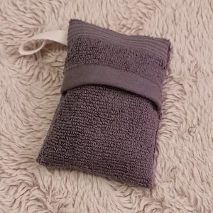 May include: A gray fabric pouch with a white drawstring closure. The pouch is made of a soft, absorbent material and is ideal for storing small items.