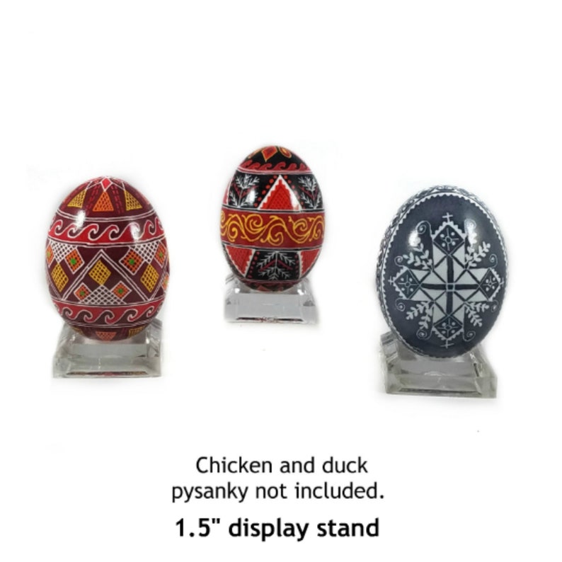 May include: Three hand-painted pysanky Easter eggs on 1.5 inch clear acrylic display stands. The eggs are decorated with geometric patterns in red, black, white, and gold. The eggs are on a white background. Chicken and duck pysanky not included.