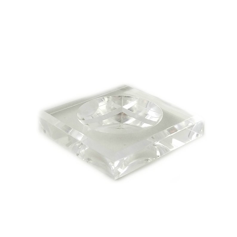 May include: A clear glass square dish with a round indentation in the center. The dish is made of crystal and has a polished finish.