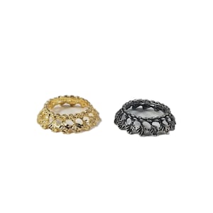 May include: Two decorative rings with a leaf design. One ring is gold and the other is black.