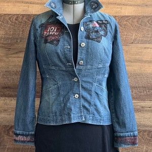 May include: A blue denim jacket with patches on the front and sleeves. The patches include the text "101 Ranch" and "Wild West Real".
