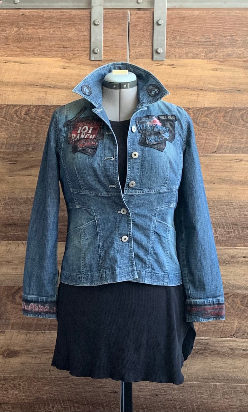 May include: A blue denim jacket with patches on the front and sleeves. The patches include the text "101 Ranch" and "Wild West Real".