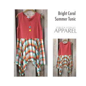 Pu&ograve; includere: Una tunica corallo senza maniche con una gonna a quadri. La tunica ha tre bottoni colorati sul davanti. La gonna &egrave; a quadri con rosso, verde, giallo e bianco. Il testo "Bright Coral Summer Tunic" e "GREEN STREET APPAREL" &egrave; visibile nell'immagine.
