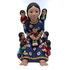 May include: A ceramic figurine depicting a woman surrounded by children. The woman wears a blue dress with pink floral accents. The children are dressed in various colors, including red, green, and purple. The figurine has a matte finish.