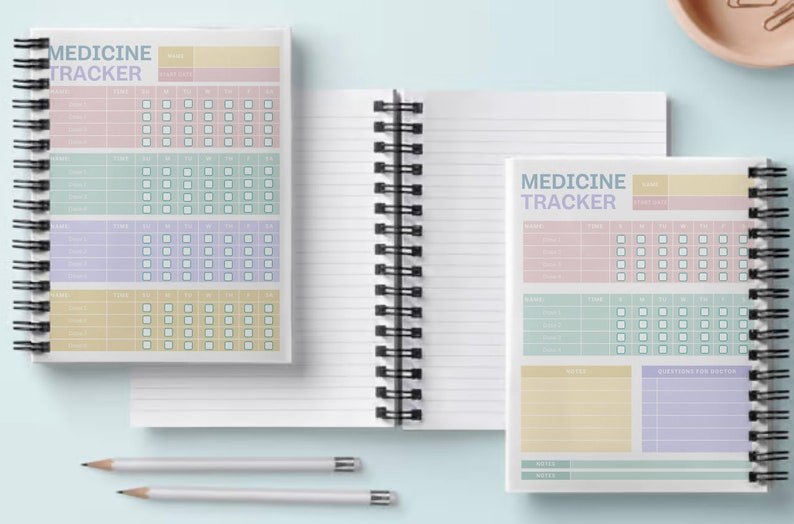 May include: Two spiral bound notebooks with lined pages and a medicine tracker page. The medicine tracker page has sections for name, time, and days of the week. The notebook covers are white with black spiral binding.