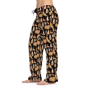 May include: Black pajama pants with a pattern of orange and white cats. The pants have a drawstring waist.