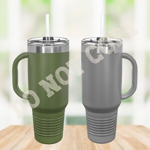 Puede incluir: Dos tazas de viaje de acero inoxidable con asas y tapas. La taza de la izquierda es verde y la taza de la derecha es gris. Ambas tazas tienen pajitas.