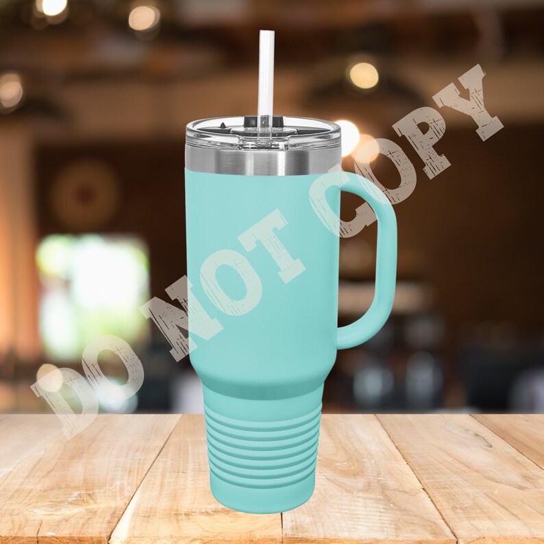 Puede incluir: Una taza de viaje de acero inoxidable azul claro con asa y pajita. La taza tiene un fondo texturizado y una tapa.