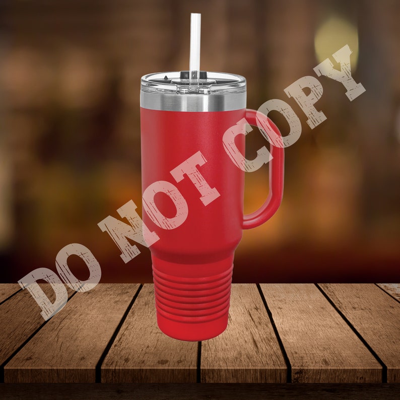 Puede incluir: Taza de viaje de acero inoxidable roja con asa y pajita. La taza tiene un fondo texturizado y una tapa con un agujero para la pajita.