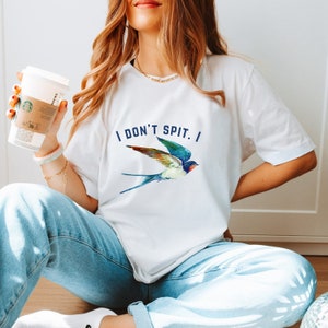 May include: White t-shirt with a blue swallow graphic and the text "I DON'T SPIT. I" printed on the front.