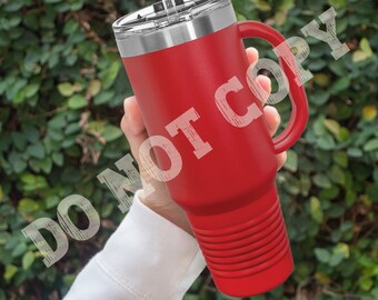 Puede incluir: Una taza de viaje de acero inoxidable roja con asa y tapa. La taza tiene un fondo texturizado y una pajita.