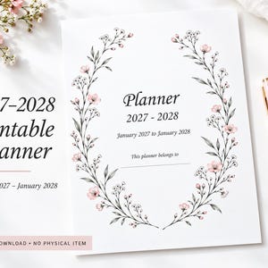 May include: A white printable planner cover for 2027-2028 featuring a central oval wreath of delicate black line-art branches with small pink flowers. The text reads Planner 2027-2028, January 2027 to January 2028, and This planner belongs to.