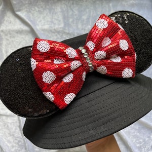 May include: Black bucket hat with a red and white polka dot bow and black sequined mouse ears.