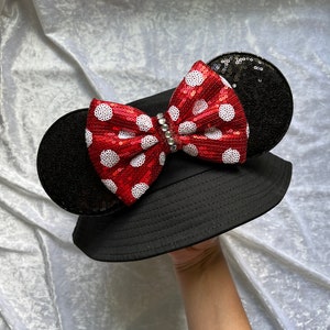 May include: Black bucket hat with a red and white polka dot bow and black sequin ears.