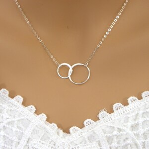 May include: A silver necklace with two interlocking circles as a pendant.