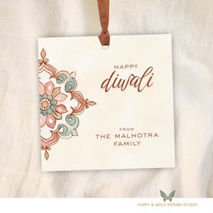 Op de afbeelding: Een vierkant, crèmekleurig cadeaulabel met een bruin lint. Het label heeft een bloemmotief in roze, teal en bruin. De woorden "HAPPY Diwali" zijn in bruin script geschreven, met "FROM THE MALHOTRA FAMILY" eronder.