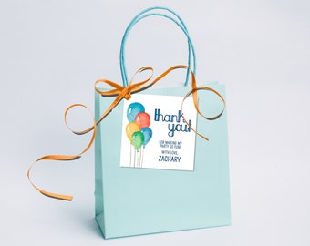May include: A light blue gift bag with a white tag featuring watercolor balloons and the words "thank you!" in navy blue. The tag also includes the text "For making my party so fun! With love, Zachary."