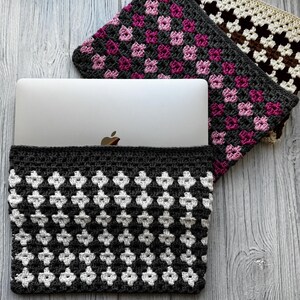 May include: A gray and white crocheted laptop sleeve with a geometric pattern, holding a silver laptop. Two additional crocheted cases in pink and brown floral patterns are visible.