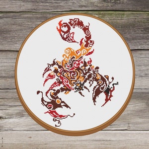 May include: A cross-stitch embroidery hoop with a colorful scorpion design. The scorpion is made up of intricate patterns in shades of red, orange, brown, and black.