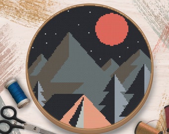 May include: A cross-stitch embroidery hoop featuring a design of a mountain range, a red sun, and a tent under a starry night sky.