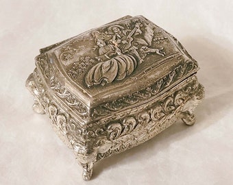 Square silver metal trinket box, attractive design with 3 figures in a garden, sits on 4 feet with red velvet covered interior-12.5cm