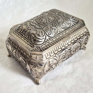 Rectangular silver metal trinket box, attractive decorative floral design, sits on 4 feet, blue velvet covered interior-made in Japan-11cm