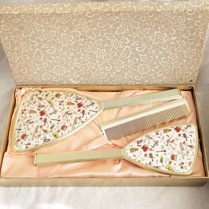 Boxed vintage 3 piece gold vanity set, attractive musical instrument pattern in beige, blue, red, black and beige, mirror, hairbrush & comb