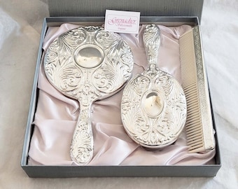 Boxed vintage 3 piece silver plated vanity set by Grenadier, embellished with an attractive embossed floral design, mirror, comb and brush