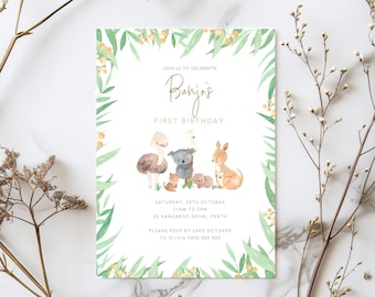 Puede incluir: Una tarjeta de invitación blanca con letras doradas rodeada de un borde floral verde y amarillo. El texto dice "Únete a nosotros para celebrar el primer cumpleaños de Banjos". La invitación incluye detalles para una fiesta de cumpleaños con fecha, hora y lugar. La tarjeta presenta una ilustración de acuarela de un grupo de animales australianos, incluyendo un koala, un canguro, un emú y un kookaburra.