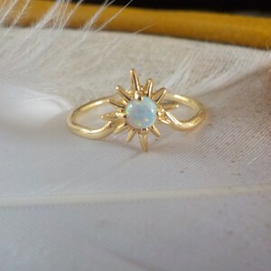 Peut inclure: Bague en or avec une pierre d'opale blanche sertie dans un motif en étoile.