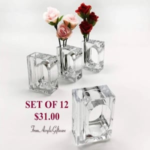 Pode incluir: Conjunto de 12 argolas de guardanapo de acr&iacute;lico transparente. Cada anel tem um pequeno vaso no centro para uma &uacute;nica flor ou ramo. O texto "SET OF 12 $31.00 From Acrylic Giftware" &eacute; vis&iacute;vel na imagem.