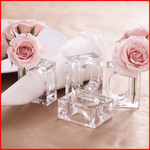 Pode incluir: Quatro argolas de guardanapo de vidro transparente com um design quadrado. Cada anel tem uma pequena abertura na parte superior para segurar uma &uacute;nica rosa rosa.