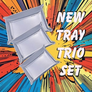 May include: A set of three silver-colored trays with curved edges, arranged in a layered composition. The background features a vibrant, comic book-style burst of orange, yellow, red, and blue. The text "NEW TRAY TRIO SET" is displayed in white.