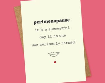 May include: A greeting card with the text "perimenopause" and the phrase "it's a successful day if no one was seriously harmed." The card has a drawing of lips and a red heart on a cream background, with a brown envelope, set against a pink backdrop.