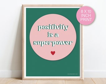 May include: An 8x10 inch print with a green background and a pink circle in the centre. The circle has the text "positivity is a superpower" in white letters. A small red heart is in the centre of the circle.
