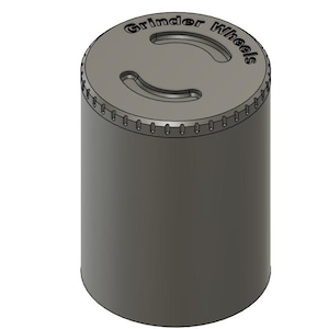 May include: A cylindrical, dark gray grinder with a textured top. The top features the words "Grinder Wheels" and two curved cutouts. The body of the grinder is smooth and solid, with a slightly angled top edge.