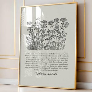 Puede incluir: Una impresión enmarcada con una ilustración botánica en blanco y negro de flores y hojas. La impresión incluye texto de Efesios 3:14-19, sobre un fondo neutro, dentro de un marco dorado.