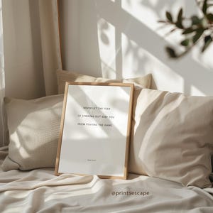 Inspirational sports quote print with simple typography, styled in a cozy bedroom with natural sunlight streaming onto neutral linens.
