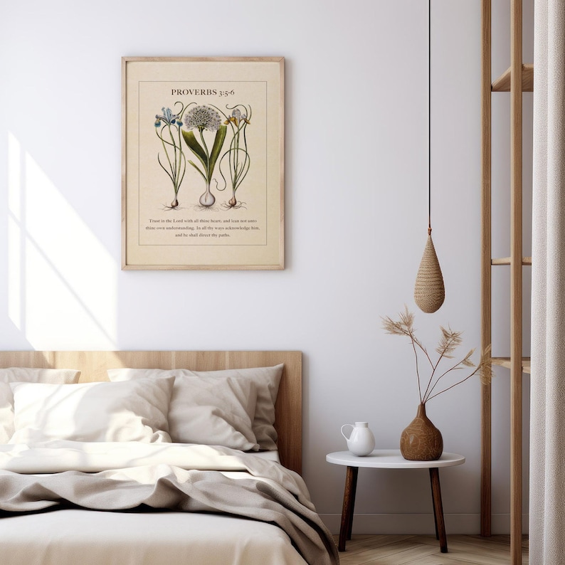 Printable featuring Proverbs 3:5-6 Bible Verse paired with illustrated vintage botanicals shown in a wood frame above a neutral bed with a vase and pitcher beside it.