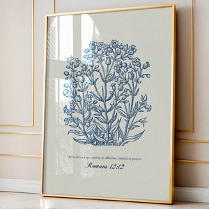 Puede incluir: Una lámina enmarcada con un dibujo botánico de líneas azules de flores silvestres sobre un fondo gris claro. Debajo de la ilustración, el texto dice: Be joyful in hope, patient in affliction, faithful in prayer. Romans 12:12.