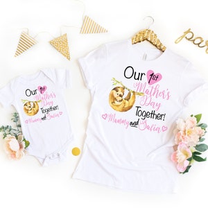 May include: White t-shirt and onesie set with a pink heart and a sloth design. The text reads "Our 1st Mother's Day Together! Mommy and Salia".