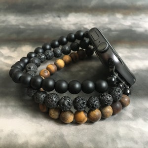 May include: A black smartwatch with a black beaded band. The band is made of three strands of beads: black lava rock, black onyx, and tiger's eye.