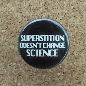 May include: A black button with white text that reads "Superstition doesn't change science."